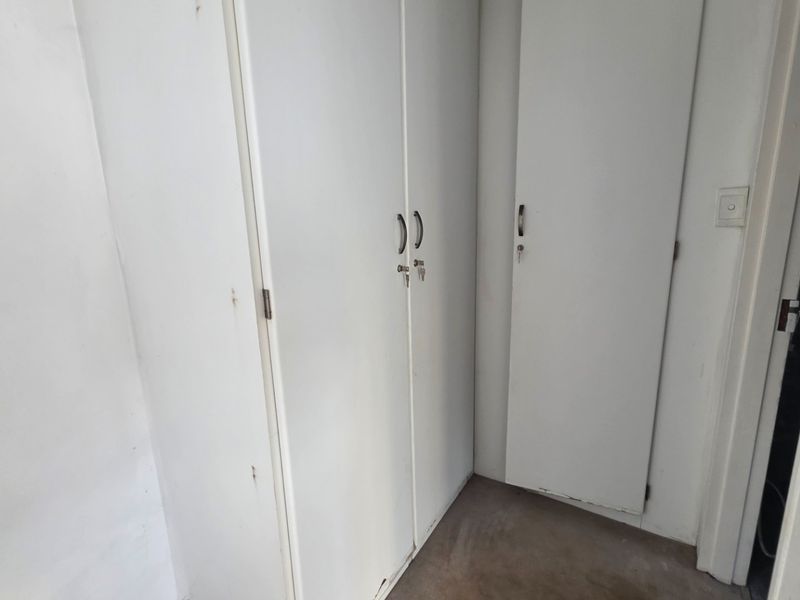 A functional hallway area featuring built-in storage cupboards with white finishes, showing signs of wear and requiring minor cosmetic maintenance.