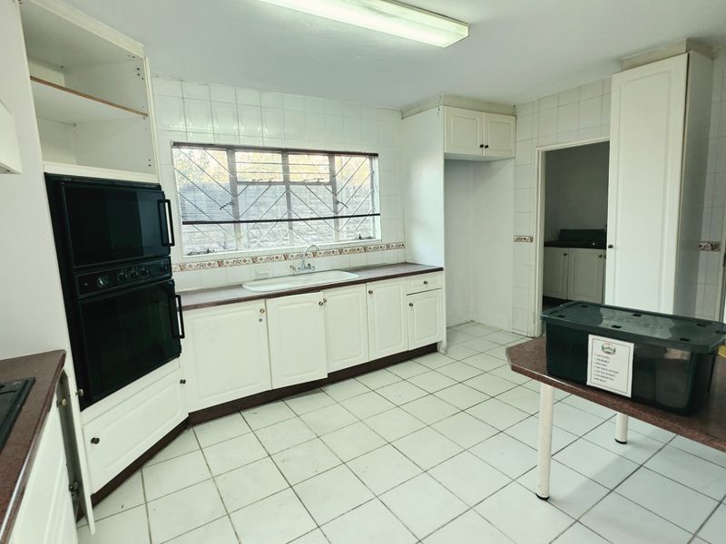A dated kitchen featuring white cabinetry, a built-in oven, hob, and tiled surfaces, offering a blank canvas for modern renovation.