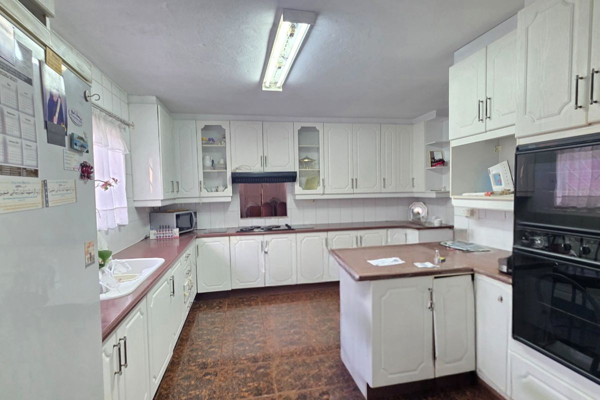 A functional kitchen featuring white built-in cabinetry, laminate countertops, integrated oven, and hob, offering a classic layout with ample storage space.