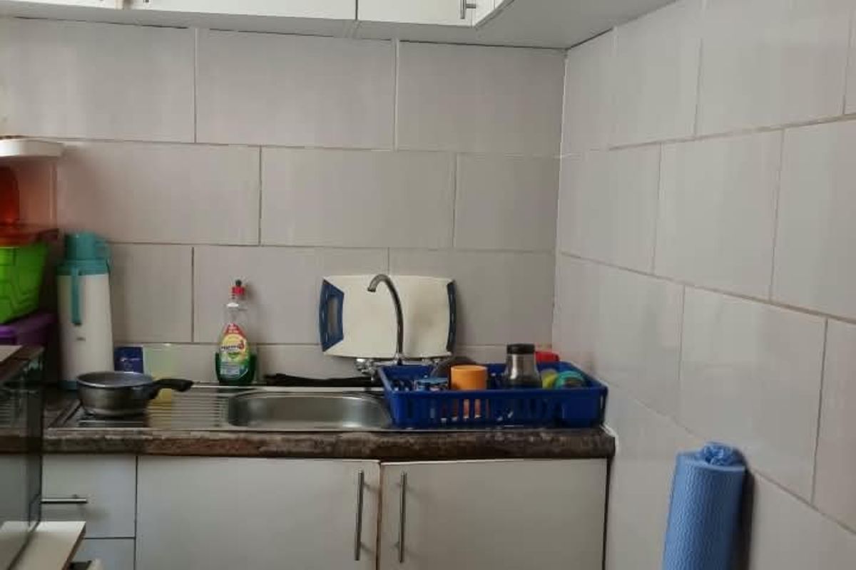 A compact kitchen featuring white built-in cabinetry, a stainless steel sink, tiled backsplash, and a functional layout for efficient meal preparation.