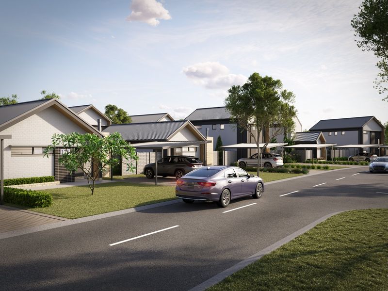 A street-level view of a modern residential estate featuring contemporary homes with pitched metal roofs, brick facades, and integrated carports.