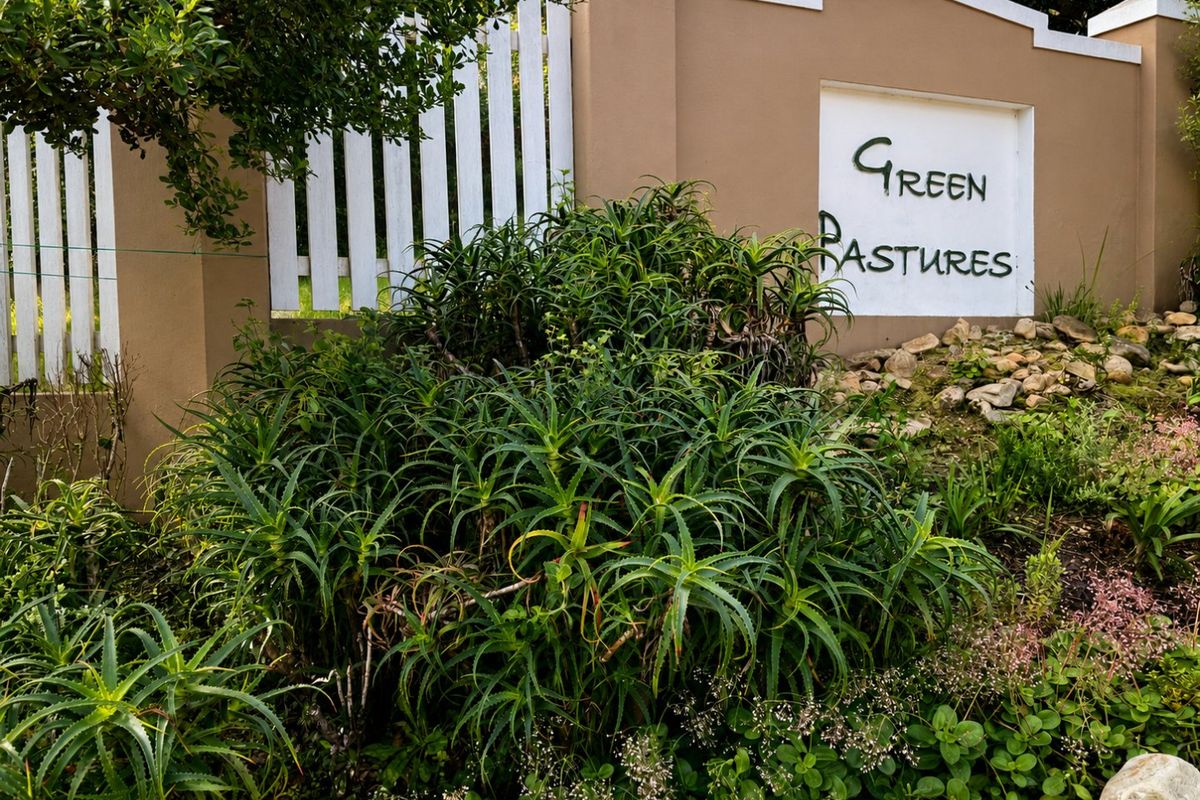 A well-maintained entrance wall and picket fence featuring established aloe plants and garden landscaping at the Green Pastures property entrance.