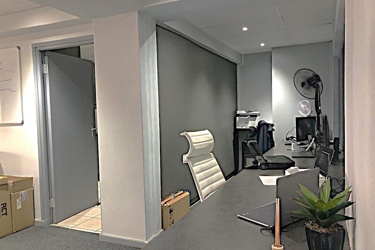 A functional commercial office space featuring a built-in desk, recessed ceiling lighting, and neutral finishes, suitable for a professional work environment.
