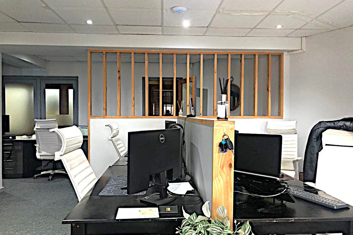 Commercial office space featuring a suspended ceiling with recessed lighting, carpeted flooring, and a decorative timber partition screen separating workstations.