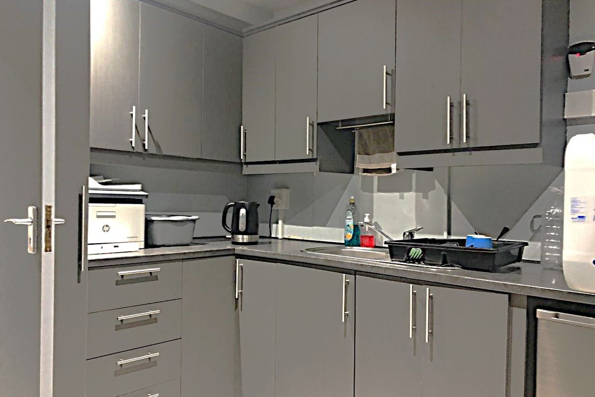 A compact kitchen area featuring modern grey cabinetry, laminate countertops, and a stainless steel sink with a mixer tap.