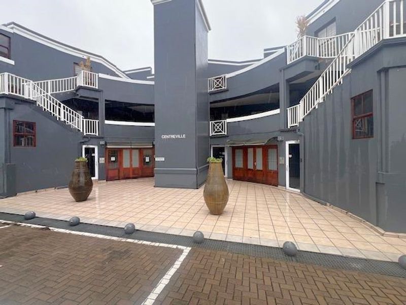 Exterior view of the Centreville commercial building featuring a paved courtyard, central tower, and multiple access points with staircases and balconies.