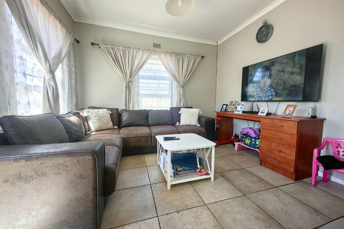 A comfortable living room featuring tiled flooring, cove cornicing, and a wall-mounted television, providing a functional space for relaxation.