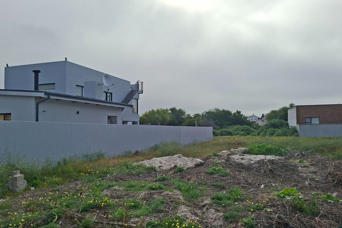 A vacant residential plot featuring natural vegetation and adjacent boundary walls, offering a blank canvas for future development.