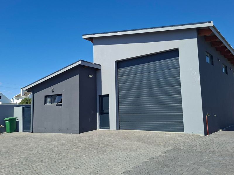 Modern detached garage featuring a large roller shutter door, paved driveway, and clean exterior finishes.