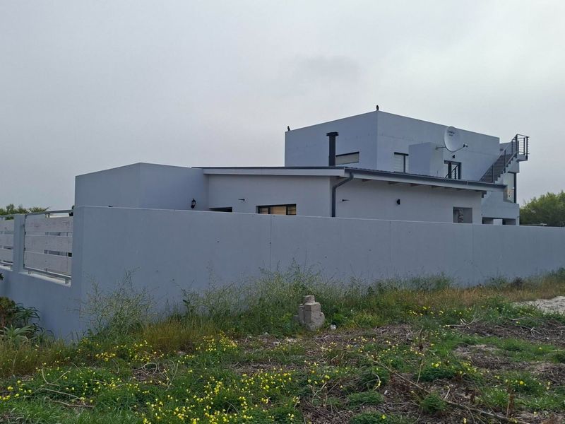 A view of the front exterior of a modern residential property featuring a boundary wall, external staircase, and clean architectural lines.