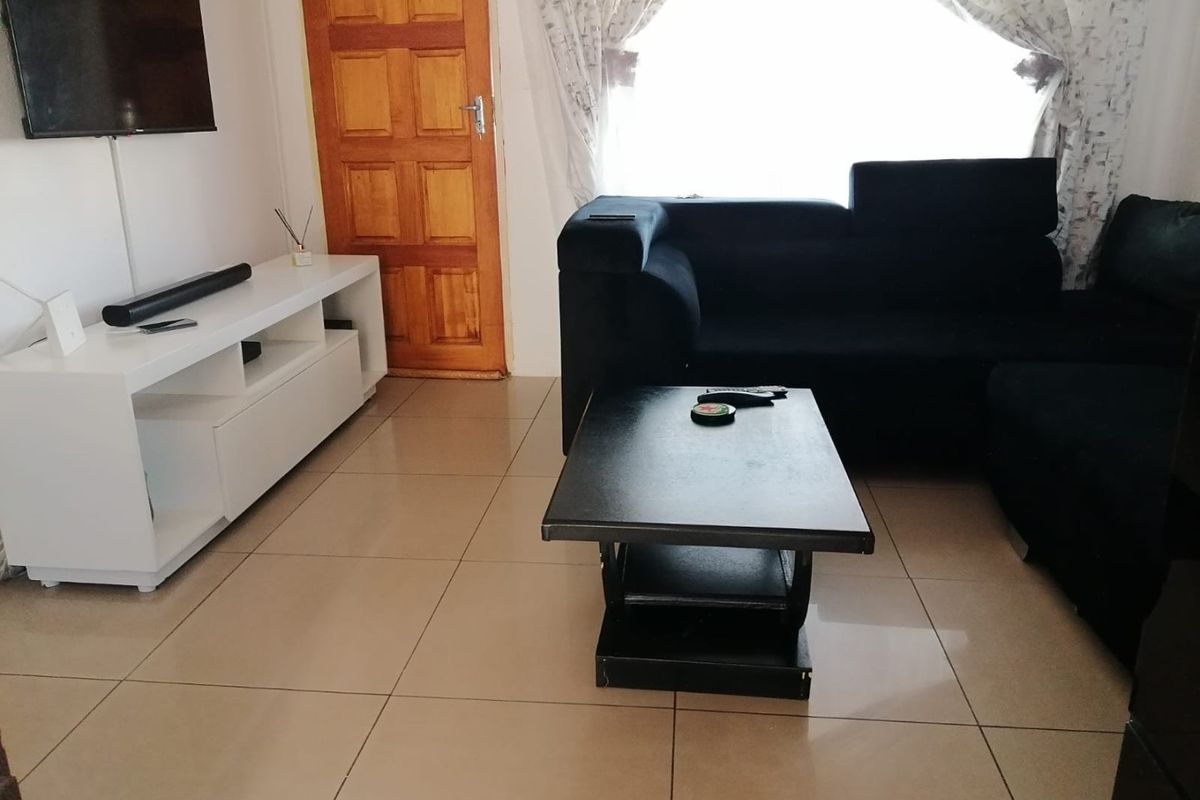 A living room featuring neutral tiled flooring and a solid timber door, providing a functional and well-lit space.