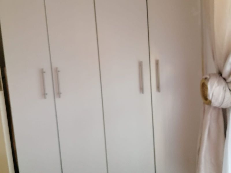 A bedroom featuring built-in cupboards with modern handles.