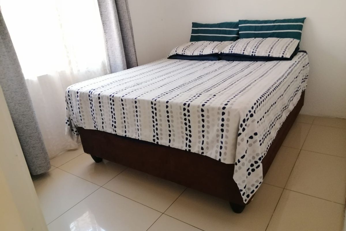 A bedroom featuring neutral tiled flooring and natural light from the window.