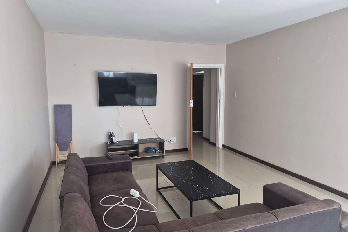 A living room featuring neutral wall paint and tiled flooring, providing a functional and open space for relaxation.