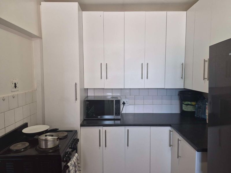 A functional kitchen featuring white cabinetry, dark countertops, a tiled backsplash, and an integrated electric stove with built-in microwave space.