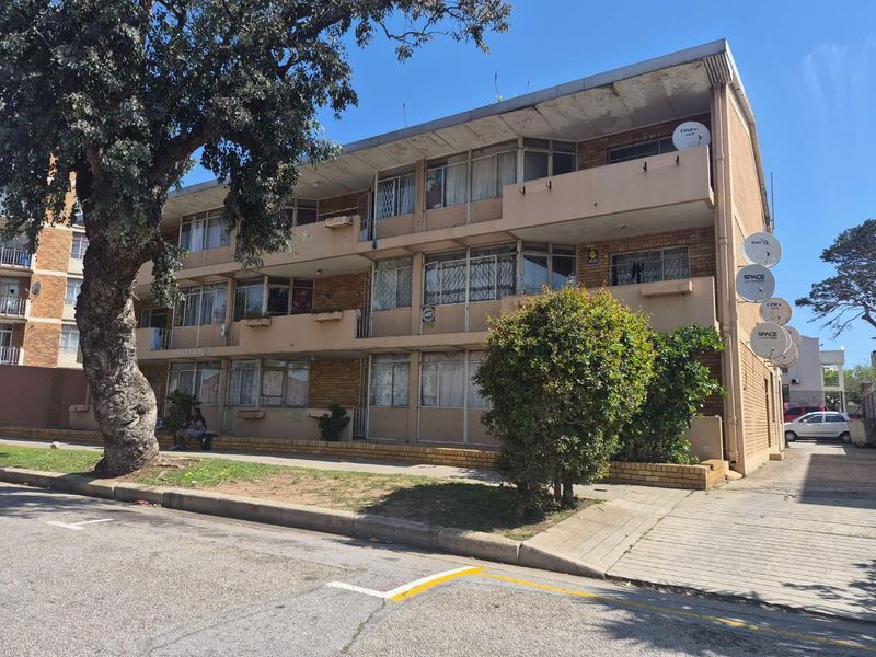 Exterior view of a multi-story apartment building featuring brick facade, balconies, and paved walkways in a residential setting.