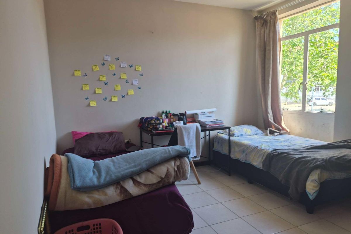 A functional bedroom featuring tiled flooring and a large window that provides natural light.