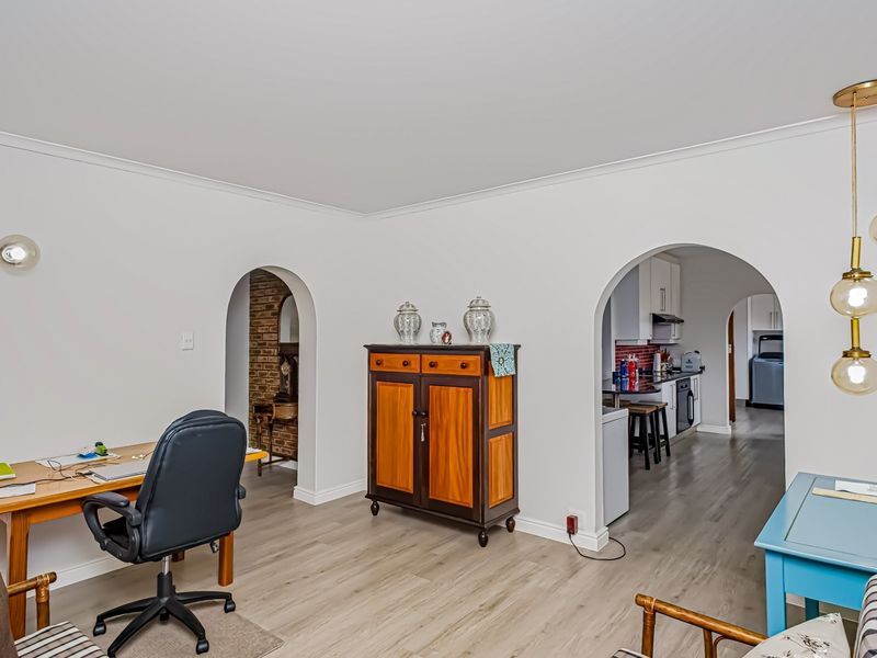 Open plan living area featuring modern laminate flooring, distinctive arched doorways connecting to the kitchen, and contemporary pendant lighting.