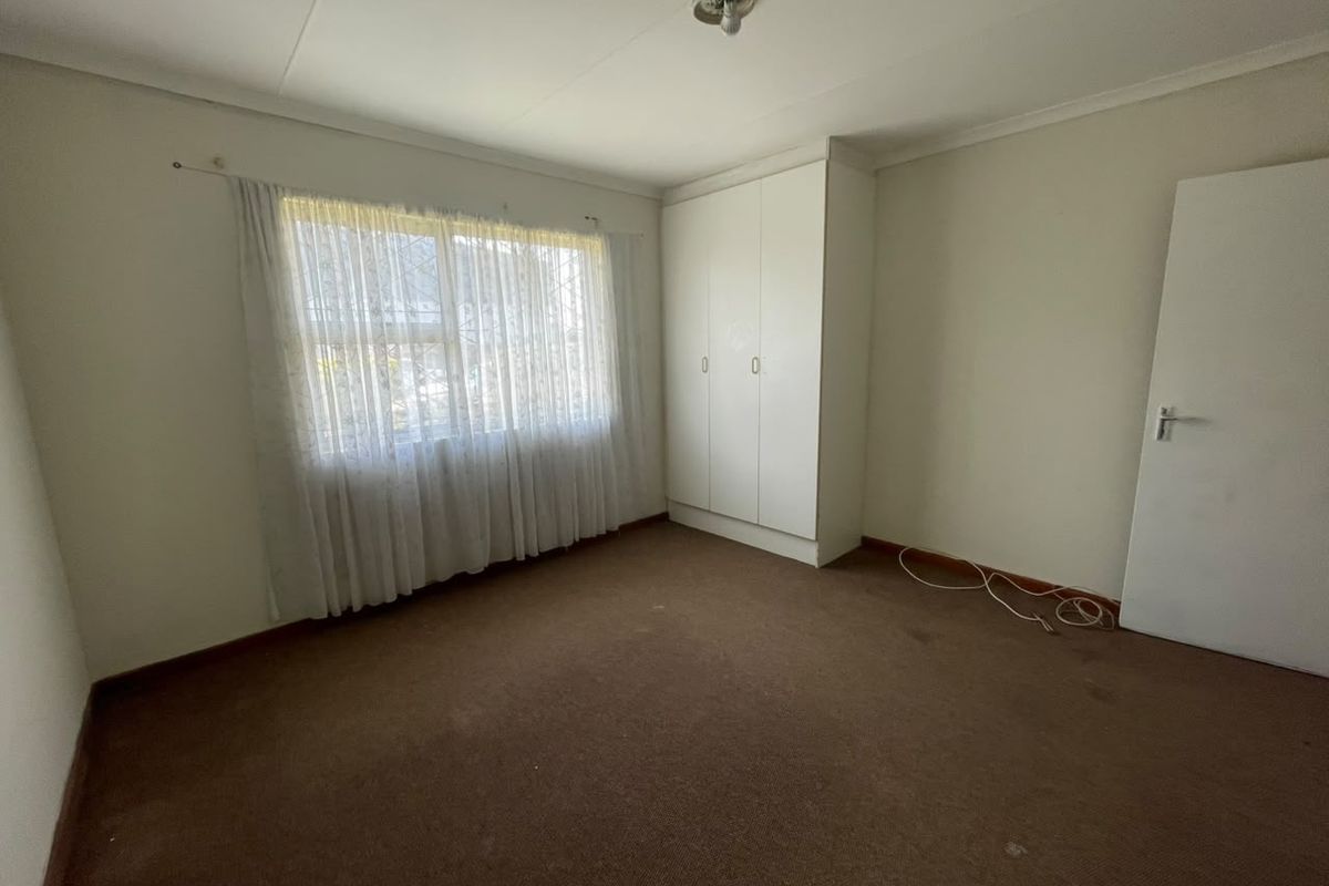 A vacant bedroom featuring built-in wardrobes, carpeted flooring, and neutral wall finishes, offering a blank canvas for potential updates.