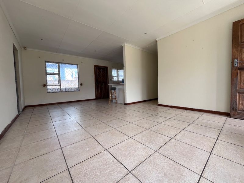 An open-plan living area featuring ceramic floor tiles, a breakfast bar, and neutral wall finishes, offering a blank canvas for interior design.