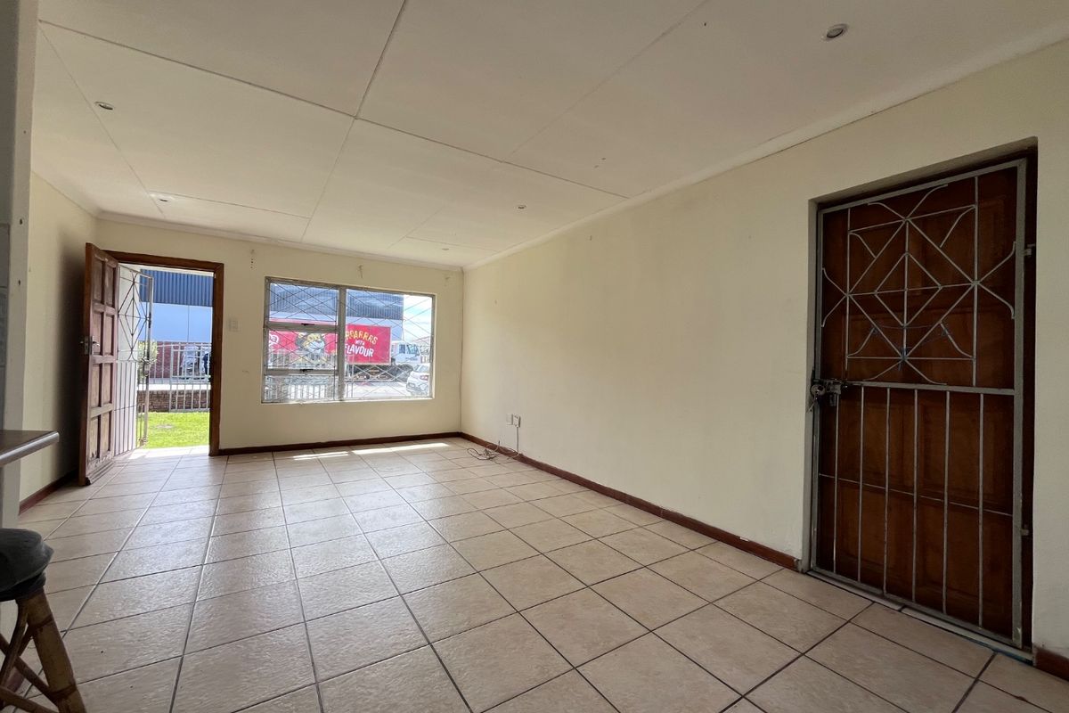 An empty living area featuring tiled flooring, recessed lighting, and secure access points with metal security gates.