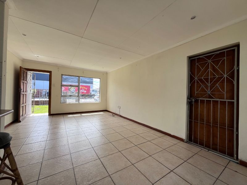 An empty living area featuring tiled flooring, recessed lighting, and secure access points with metal security gates.