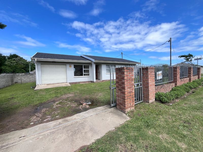 Front view of a single-story house featuring a single garage, brick boundary wall with metal gate, and a tiled roof.