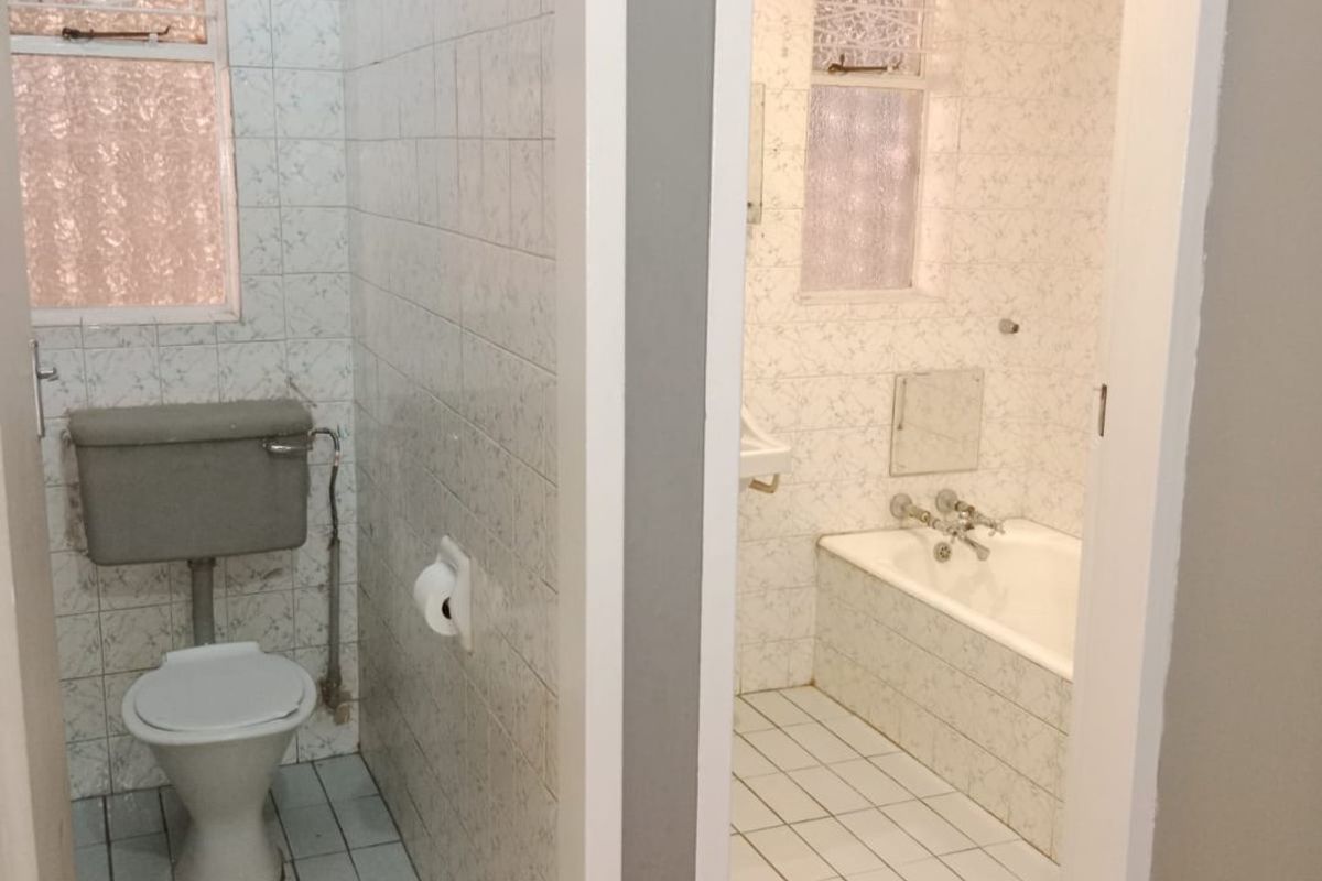 A separate toilet and bathroom suite featuring dated wall tiling and original sanitary fixtures, offering potential for a modern renovation.