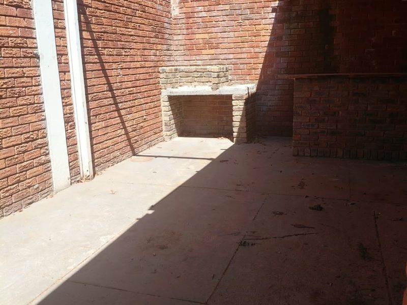 Covered outdoor patio area featuring a built-in brick braai and bar counter, offering a functional space for outdoor entertaining.