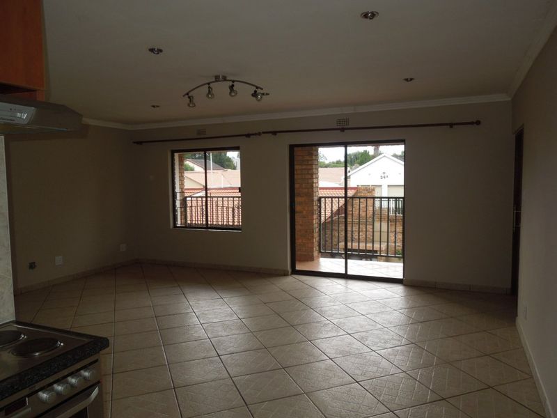 Spacious open-plan living area featuring tiled flooring, recessed lighting, and direct access to a balcony through sliding glass doors.