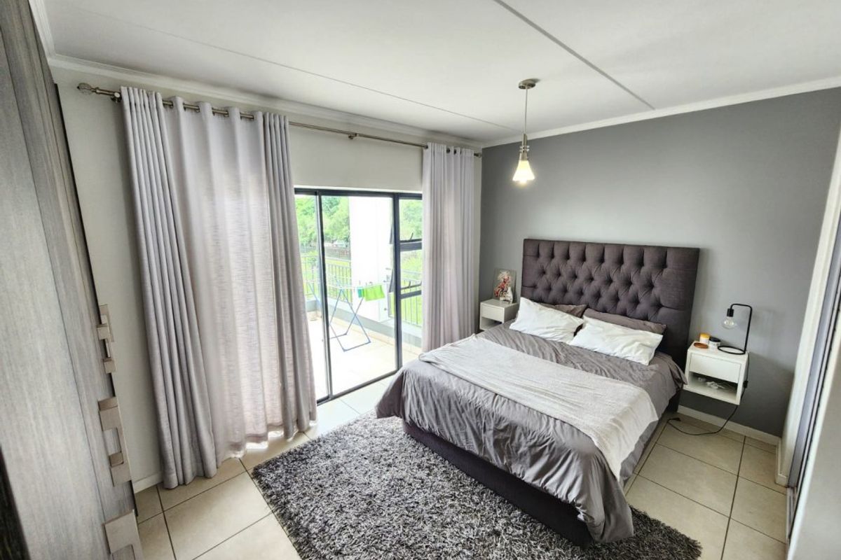 A well-maintained bedroom featuring tiled flooring, a built-in wardrobe, and a sliding glass door providing access to a private balcony.