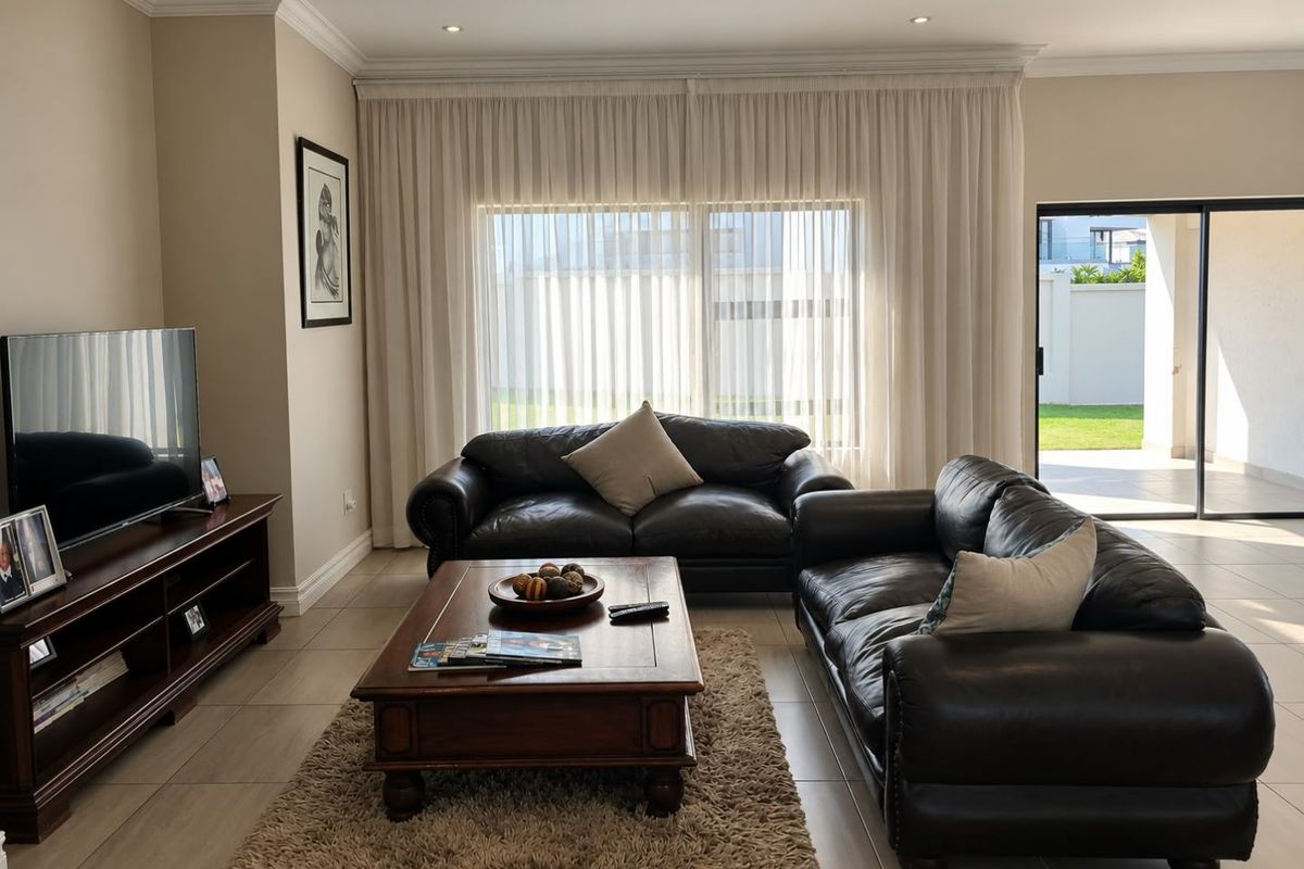 A well-maintained living room featuring tiled floors, crown molding, recessed lighting, and large sliding glass doors providing access to the outdoor patio area.