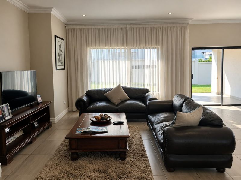 A well-maintained living room featuring tiled floors, crown molding, recessed lighting, and large sliding glass doors providing access to the outdoor patio area.