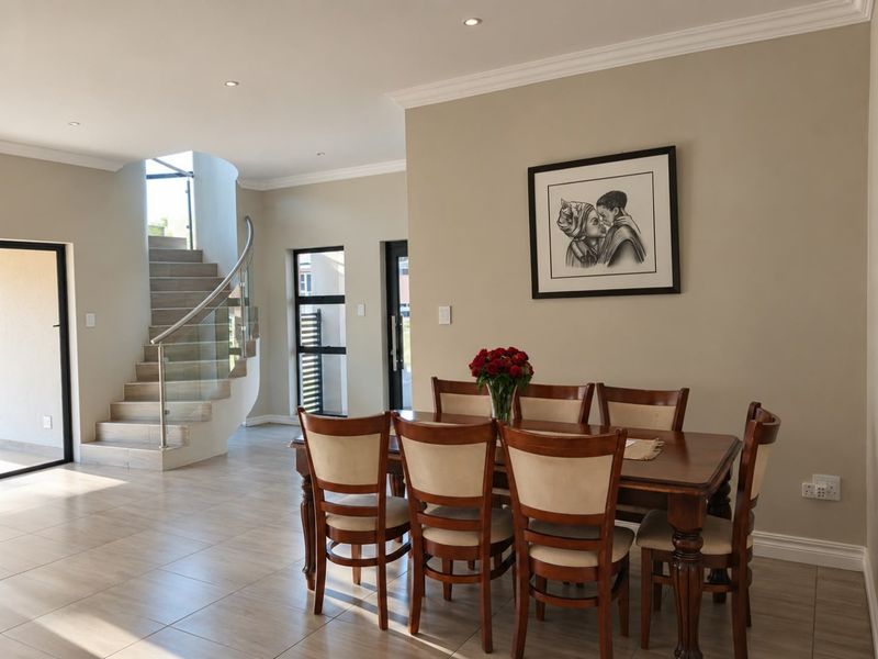 A bright and modern dining area featuring tiled floors, recessed lighting, and an elegant curved staircase with a glass balustrade.
