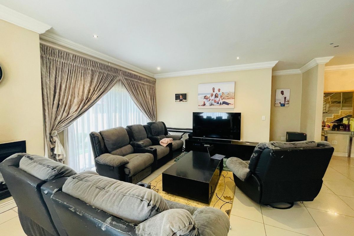 A spacious living room featuring tiled flooring, recessed downlighting, and large sliding glass doors with curtains, providing access to the exterior.
