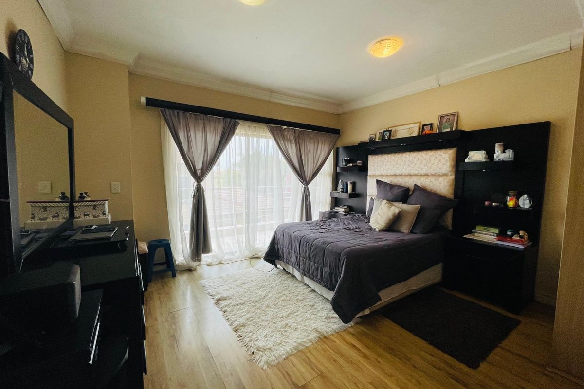 A well-maintained bedroom featuring laminate flooring, a built-in headboard with integrated shelving, and a sliding glass door providing access to an outdoor area.
