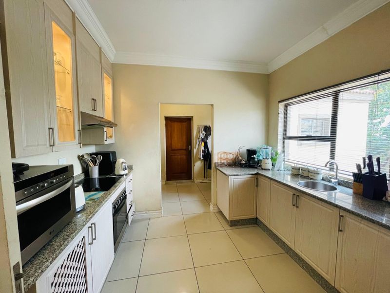 A functional kitchen featuring light-toned cabinetry, granite countertops, integrated appliances, and tiled flooring, offering a practical layout with ample storage space.
