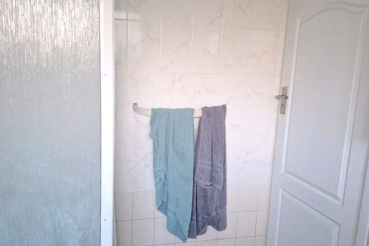 A functional bathroom featuring a shower enclosure, tiled walls, and tiled flooring, currently in need of cosmetic updates.