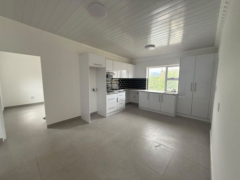 Modern kitchen featuring white cabinetry, contrasting black subway tile backsplash, tiled flooring, and a tongue and groove ceiling with integrated lighting.