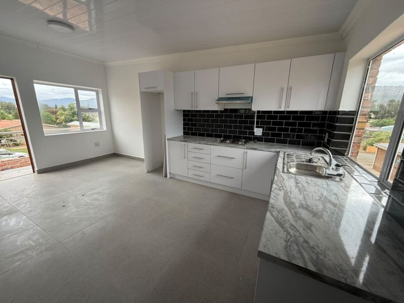 Modern kitchen featuring white cabinetry, marble-look countertops, black subway tile backsplash, and built-in gas hob, offering a clean and functional workspace.