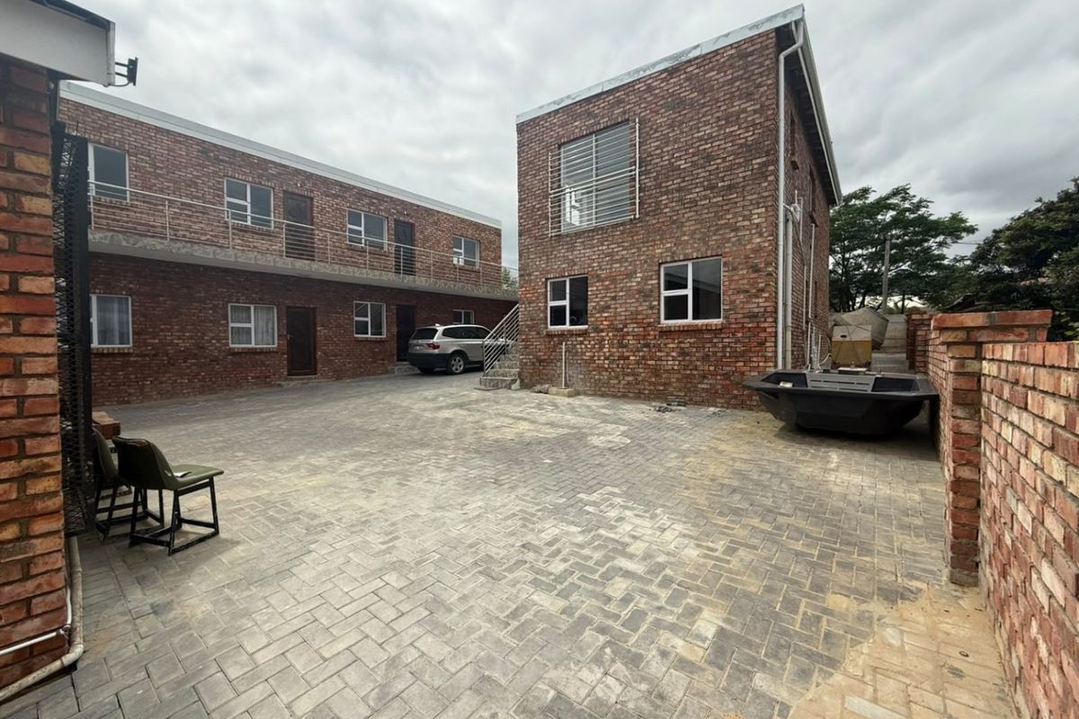 Rear courtyard area featuring face brick commercial buildings, paved ground surface, and external access staircases.