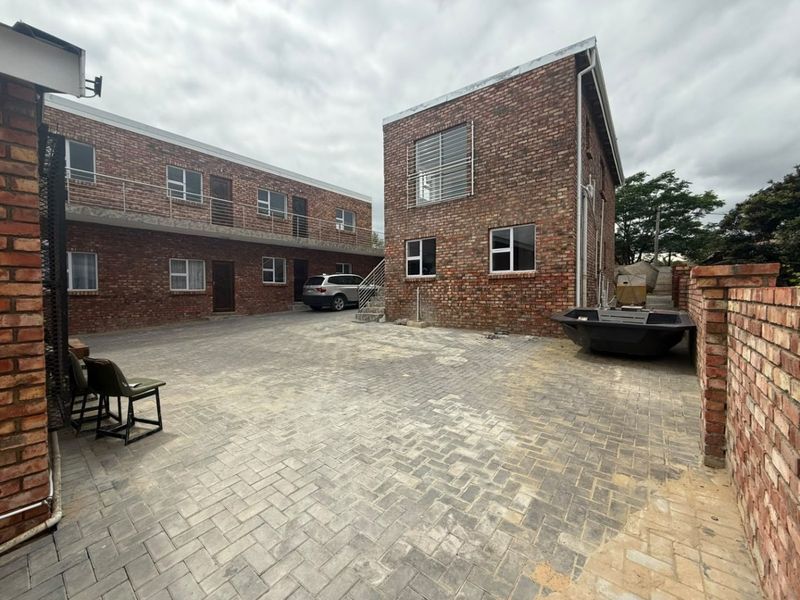 Rear courtyard area featuring face brick commercial buildings, paved ground surface, and external access staircases.