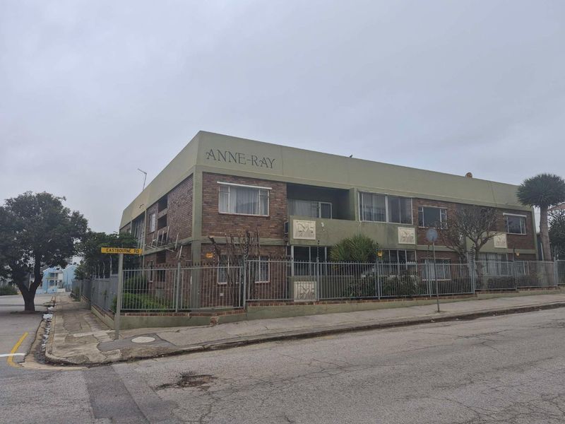 Exterior view of the Anne-Ray apartment building, featuring a brick facade, security fencing, and street-level access.