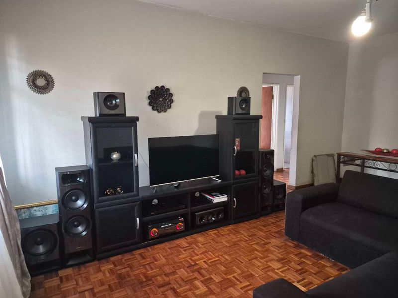 A living room featuring classic parquet flooring and a neutral wall finish, providing a functional space for relaxation and entertainment.