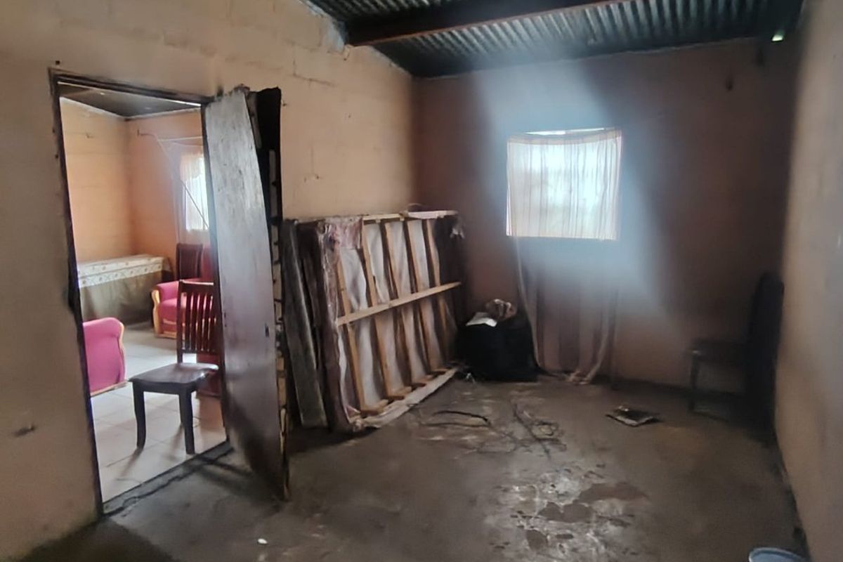 A basic, unfinished bedroom featuring exposed corrugated iron roofing, masonry walls, and a concrete floor, offering a blank canvas for renovation.