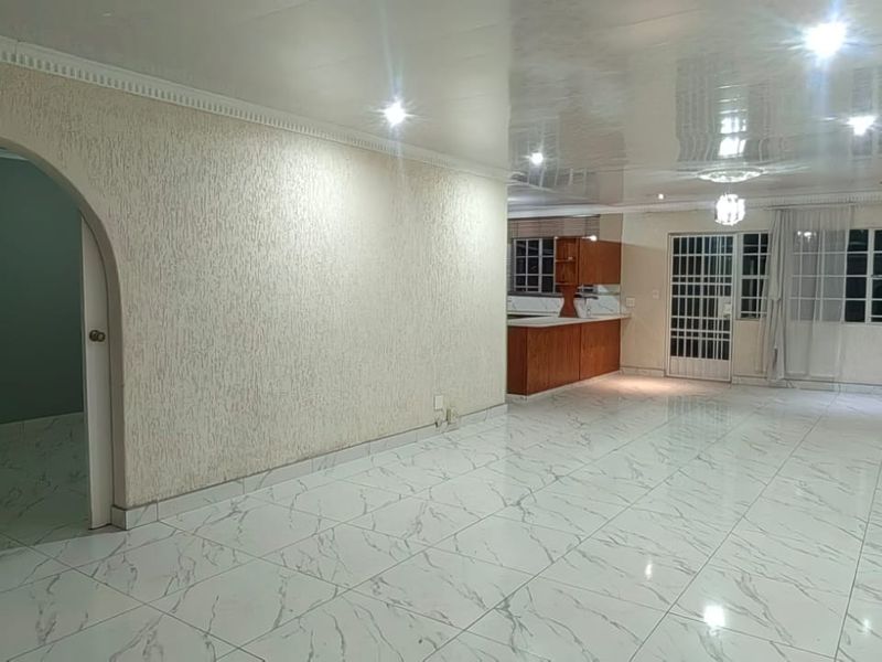 Spacious open-plan living area featuring polished marble-look floor tiles, arched architectural details, recessed lighting, and an integrated kitchen space.
