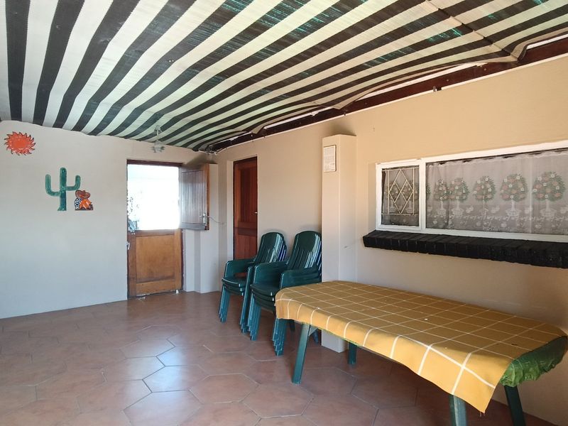 A covered outdoor patio area featuring tiled flooring, a striped fabric awning, and secure access points, suitable for outdoor relaxation and entertainment.