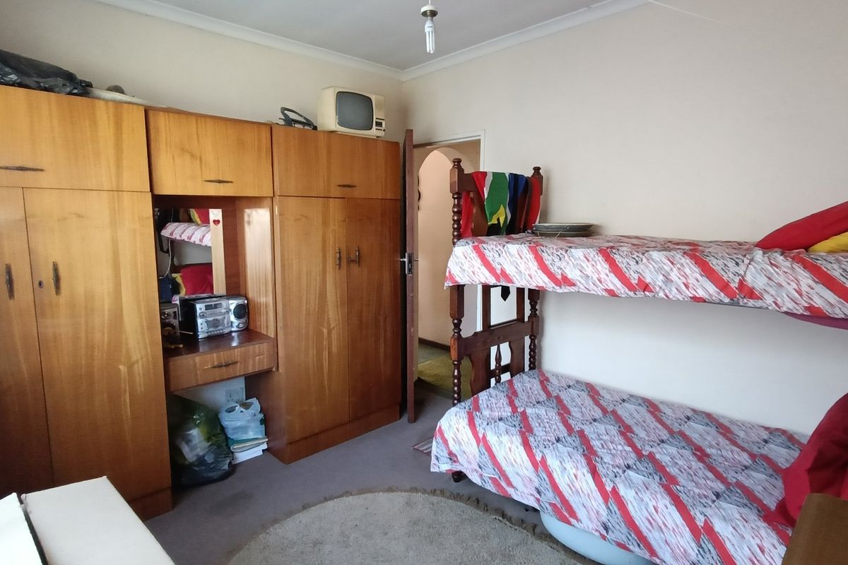 A functional bedroom featuring extensive built-in wooden cabinetry and coving, offering practical storage solutions within a standard residential layout.