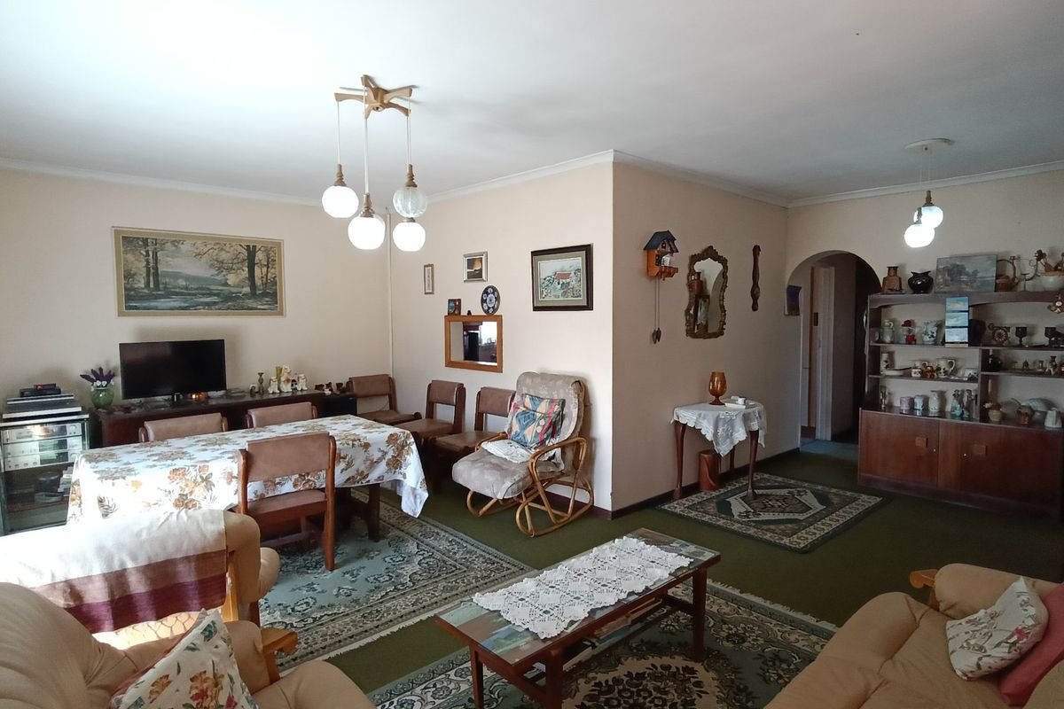 Spacious living and dining area featuring an open-plan layout with an arched entryway and classic pendant lighting.