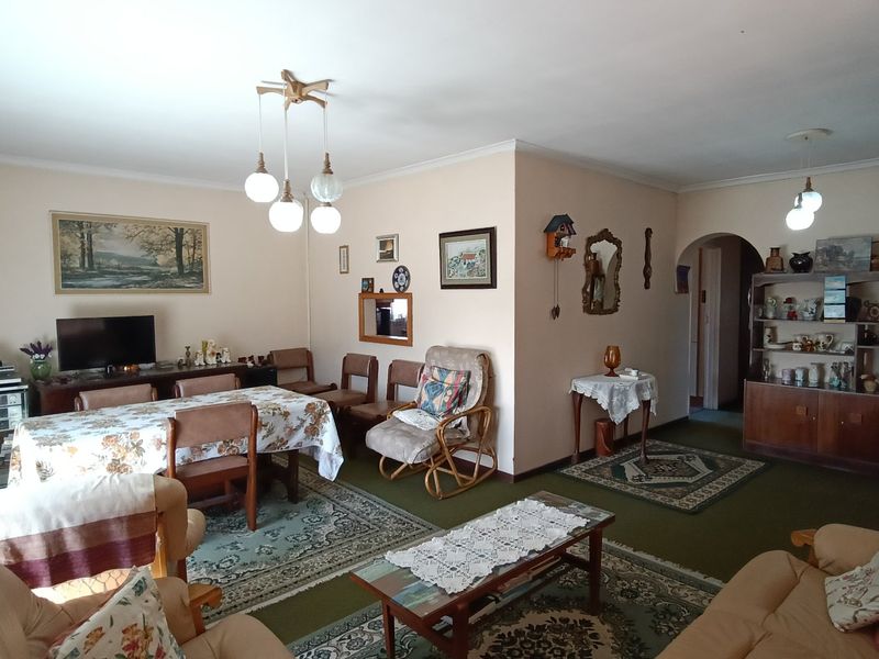 Spacious living and dining area featuring an open-plan layout with an arched entryway and classic pendant lighting.